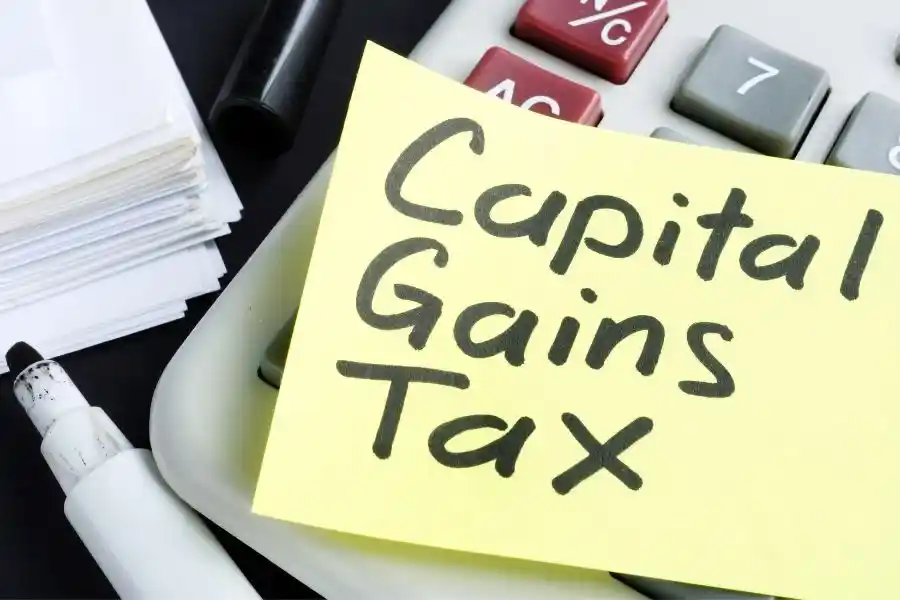 A calculator and tax documents with ‘Capital Gains Tax’ highlighted, representing strategies to reduce real estate tax liability in NY